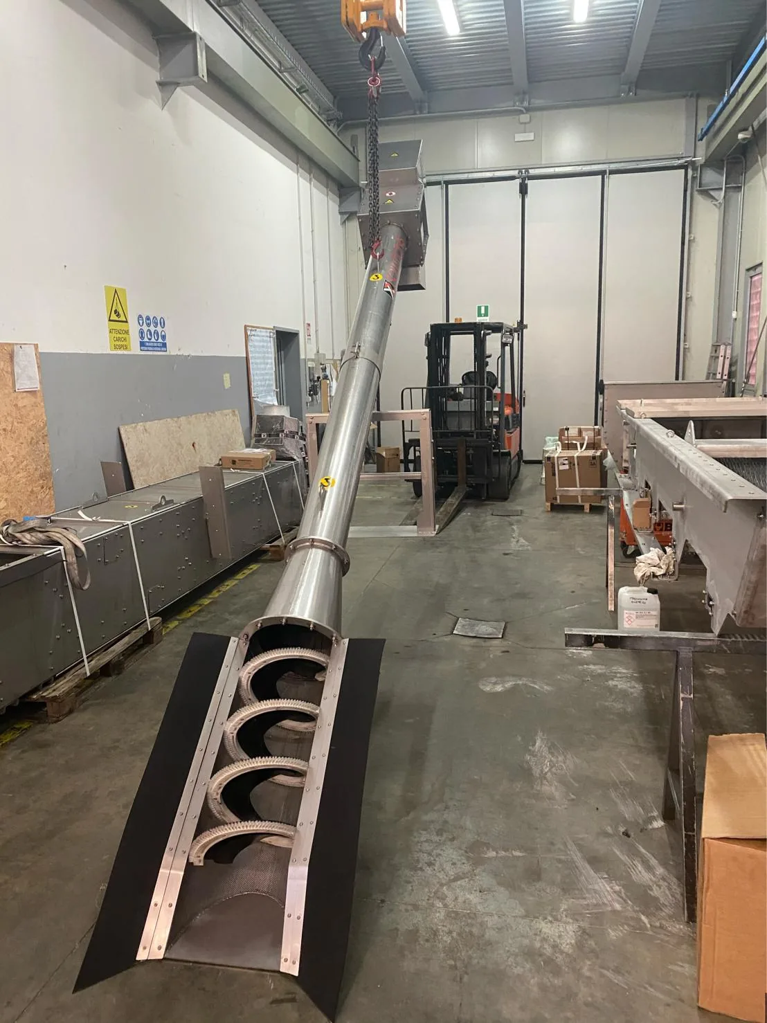 Tamis à vis canal inox Biotrade suspendu au pont roulant en atelier, montrant la grille de filtration perforée ouverte