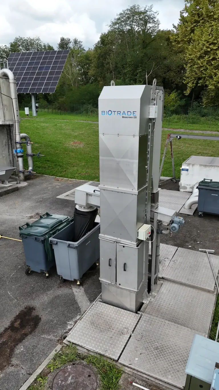 Dégrilleur BioScreen DS Biotrade vue de dessus avec logo Biotrade visible, installé sur dalle béton avec bacs de collecte des refus et panneaux solaires en arrière-plan
