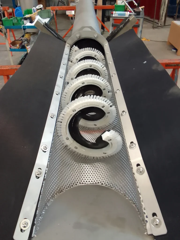 Gros plan sur la grille perforée inox et les brosses annulaires de nettoyage du tamis à vis canal Biotrade en atelier
