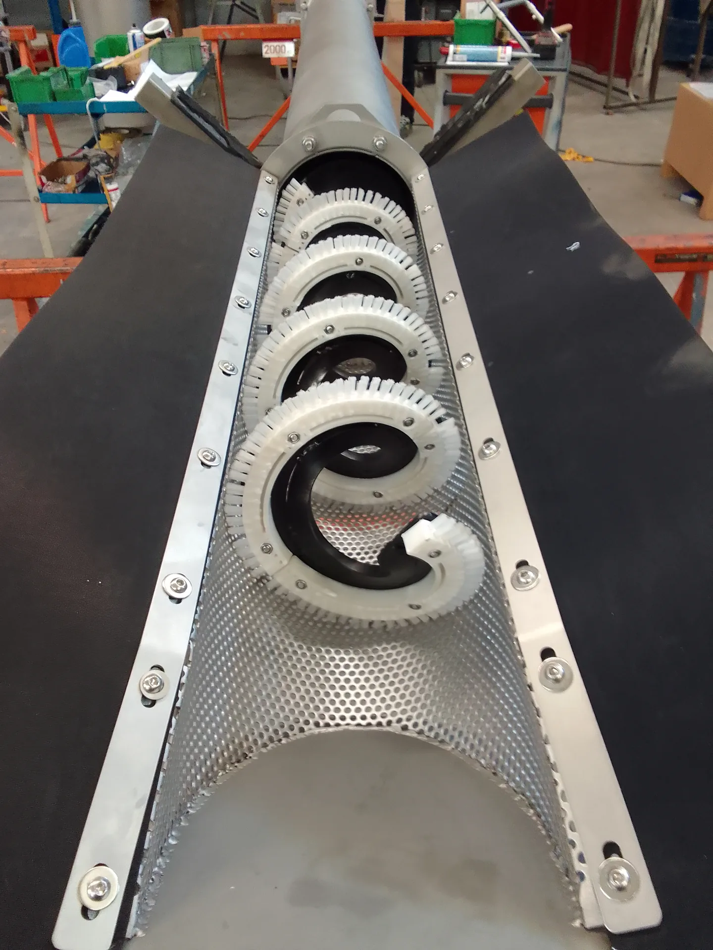 Gros plan sur la grille perforée inox et les brosses annulaires de nettoyage du tamis à vis canal Biotrade en atelier
