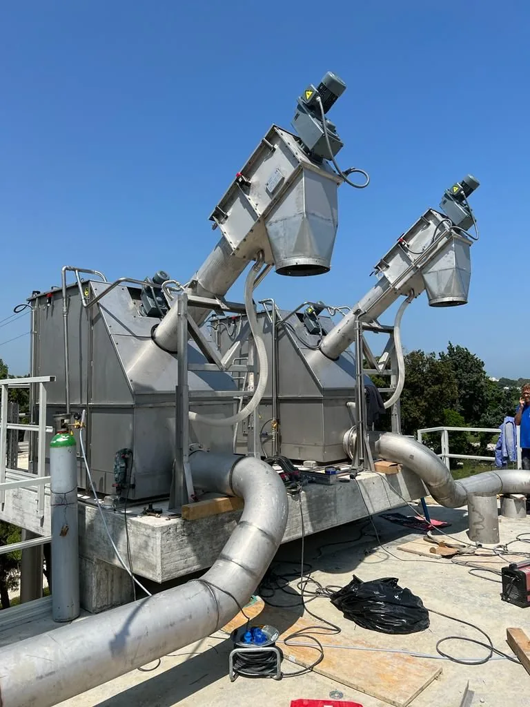 Quatre tamis à vis caisson inox Biotrade installés en parallèle sur chantier de station d'épuration, vus de trois-quarts