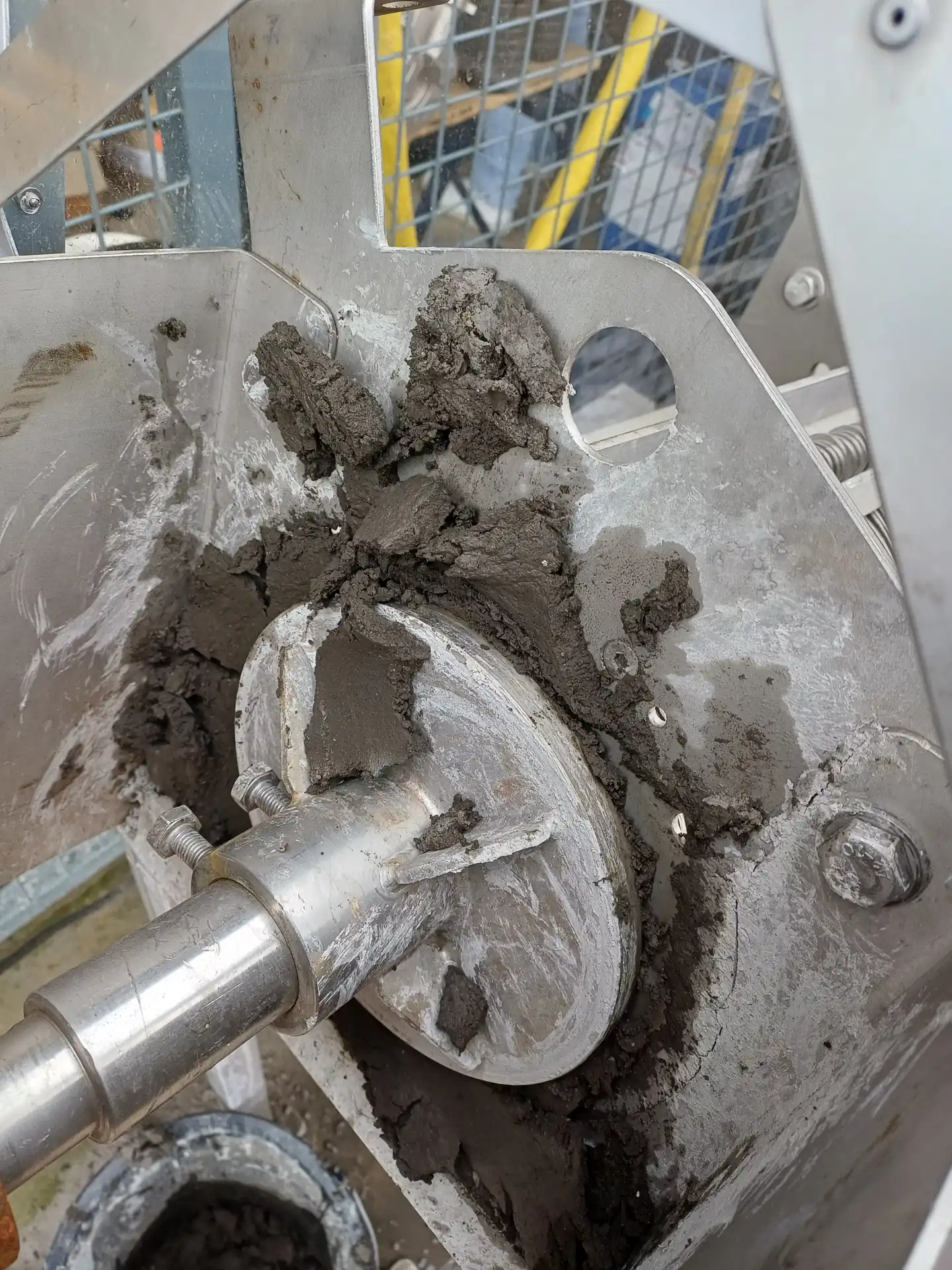 Gros plan sur la tête de sortie d'une presse à vis Biopress Biotrade avec gâteau de boues grises compactes lors d'un essai pilote
