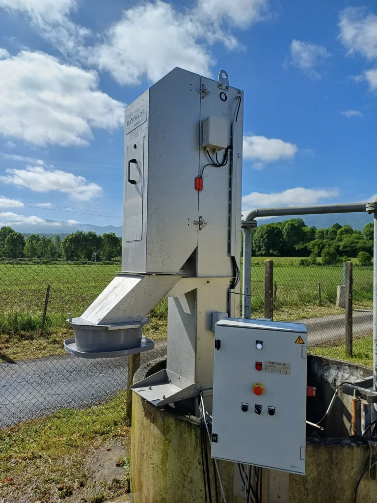 Dégrilleur BioScreen BV Biotrade installé à l'extérieur d'une station d'épuration rurale, avec coffret électrique visible et paysage agricole en arrière-plan