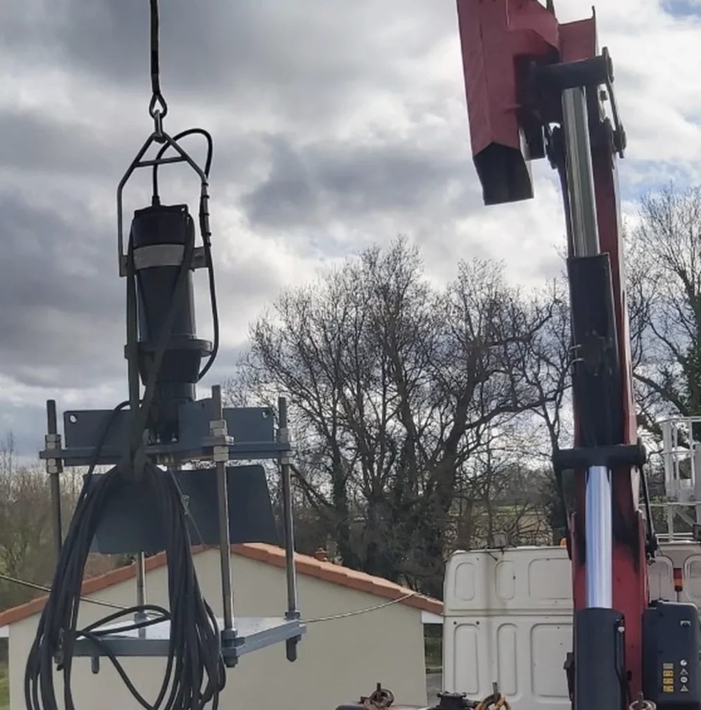 Mélangeur immergé Biotrade suspendu à une grue hydraulique lors de son installation dans un silo de stockage de boues ou de digestat