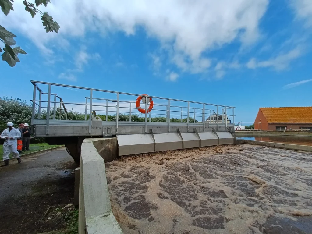Nouveau pont brosse Biotrade en aluminium installé au-dessus d'un bassin d'aération en activité dans le Pas-de-Calais, avec techniciens en tenue de sécurité et boues en surface